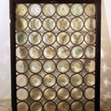 A mouth blown window with round partly coloured glass in tin net with iron wind protection in wooden frame - фото 1