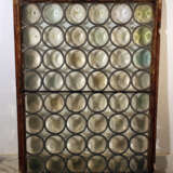 A mouth blown window with round partly coloured glass in tin net with iron wind protection in wooden frame - фото 2