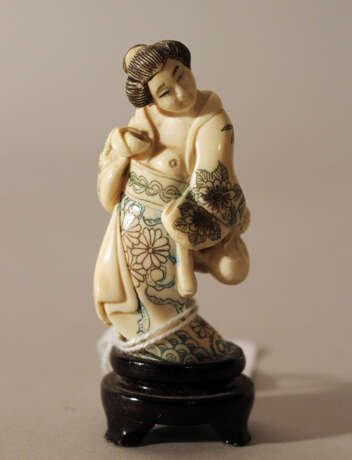 Japanese ivory netsuke showing a woman holding a baker and a bag in traditional dress, partly engraved - Foto 1