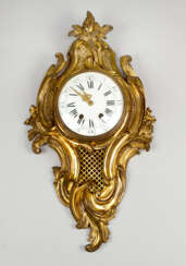A French Louis XV style cartel clock, decorated with volutes and flowers, the fields with partly open work grid