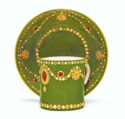 A SEVRES PORCELAIN OLIVE-GREEN GROUND 'JEWELED' CUP AND SAUC...