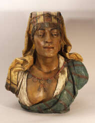 A Goldscheider terracotta bust of an oriental lady, with cape, coins and waved dress