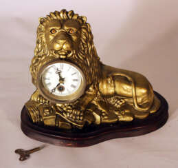 An eye turning clock in shape of a lying lion with enamel dial with Roman numbers
