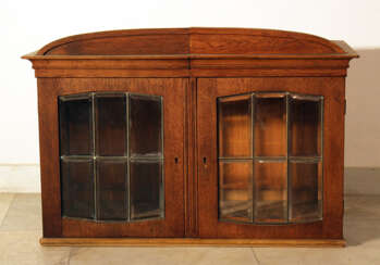 A Jugendstil display cabinet with arched top, two doors and cutted glass windows with bronze grid