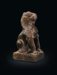 A SMALL BLACKISH STONE FIGURE OF A SEATED LION