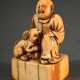 Sehr altes Elfenbein Netsuke "Mann mit Hund auf Sockel sitzend", bernsteinfarbene Patina, Japan um 1700/1720, H. 4,2cm, Provenienz: Norddeutsche Sammlung, Genehmigung nach Art. 10d VO (EG 338/97) liegt vor, kein Export außerhalb der EU - photo 1