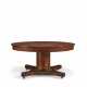 A CENTRAL EUROPEAN MAHOGANY AND PARCEL-EBONIZED CIRCULAR EXTENSION DINING TABLE - photo 1