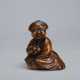 A CARVED WOOD NETSUKE OF A SEATED WOMAN HOLDING BELLS - Foto 1