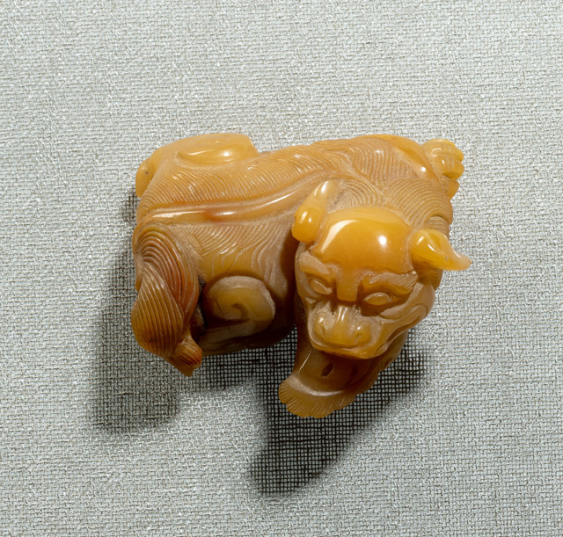 Carving of a recumbent lion made of amber agate