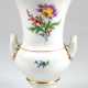 Meissen-Amphorenvase, auf rundem Fuß, mit 2 seitlichen Henkeln, auf Schauseite Bunte Blume 2 und Streublümchen, Goldränder, Schwertermarke mit 2 Schleifstrichen, H. 26 cm - photo 1