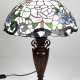 Tischlampe im Tiffanystil, 2. Hälfte 20. Jh., 1-flammig, Metallfuß in Vasenform, braun gefasst, Schirm aus farbigem Kunstglas mit Blütendekor, H. 59 cm, Dm. 40 cm - Foto 1