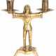 Kerzenleuchter, um 1920, Messing, über 6-passigem Stand auf 3 Füßen Männerfigur, der in den seitlich ausgestreckten Armen Kerzentüllen mit Traufschalen hält, H. 23 cm - photo 1 Kerzenleuchter, um 1920, Messing, über 6-passigem Stand auf 3 Füßen Männerfigur, der in den seitlich ausgestreckten Armen Kerzentüllen mit Traufschalen hält, H. 23 cm - photo 1