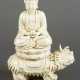 Blanc-de-Chine porcelain sculpture of Buddha sitting in lotus shaped seat, with a pot for the poor, on a fantastic animal - Foto 1