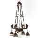 Alessandro Mazzucotelli. Small four-light wrought iron chandelier with pendant light bulbs supported by dog heads - photo 1