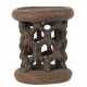 Afrikanischer Hocker aus einem Stück Holz geschnitzt, mit ringförmigem Stand und gitterartig angeordneten Miniaturmasken als Stützen der leicht ovalen Sitzfläche - photo 1