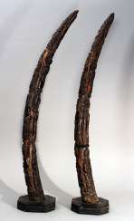 A pair of African horns with rich figural carvings on octagonal wooden bases A pair of African horns with rich figural carvings on octagonal wooden bases