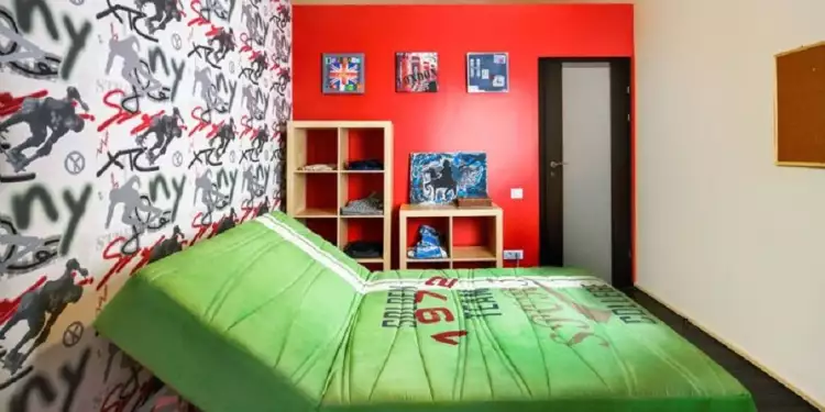 Уличный стиль в интерьере. Интерьер спальни с большой зеленой кроватью и граффити в уличном стиле