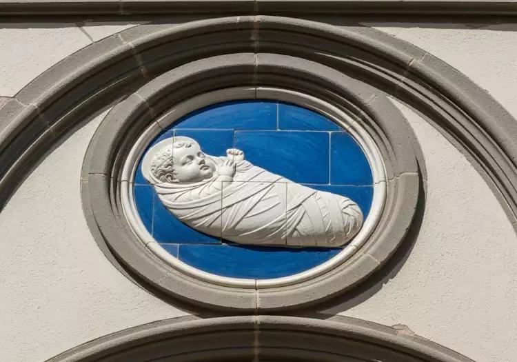 Медальон со спеленутым младенцем работы Андреа делла Роббиа с фасада Воспитательного дома (Оспедале дельи Инноченти) во Флоренции.