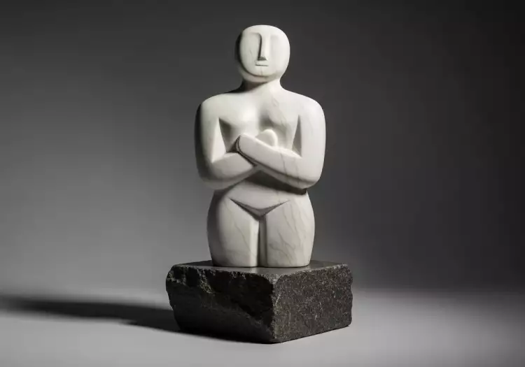 Минималистичная мраморная статуэтка с острова Киклады ('кикладский идол') с абстрактными формами и скрещенными руками.