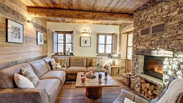 Стиль шале в интерьере. Интерьер гостиной с угловым диваной и камином, облицованным камнем в стиле шале